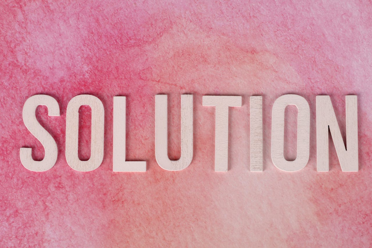 Wooden letters spelling 'Solution' on a textured pink background.